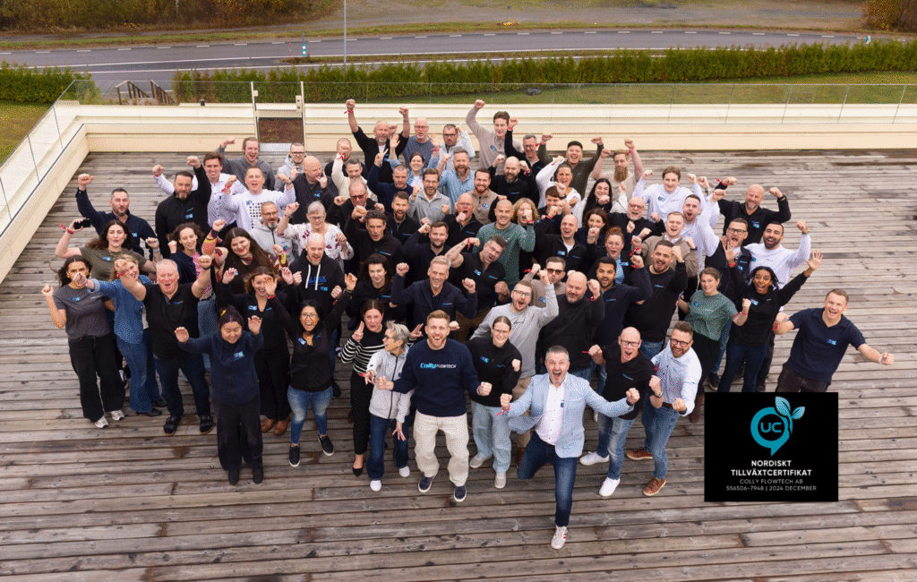 Gruppbild på hela Colly Flowtech-teamet som står utomhus och firar tillsammans, med UC Nordiskt Tillväxtcertifikat synligt i bilden.