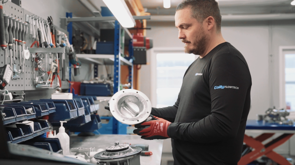 En tekniker från Colly Flowtech inspekterar en metalldel under en pumpservice i verkstaden.