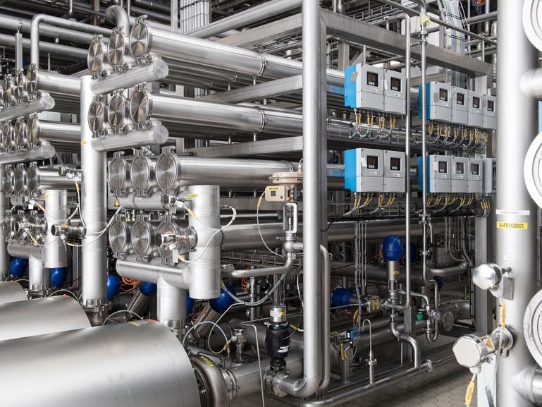 Industriell processanläggning med rostfria rör, filtermoduler och styrutrustning för membranfiltrering.